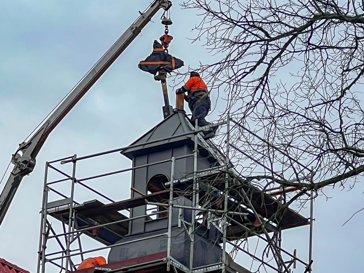 Trying on, adjusting the cross on the tower of the renovated church.
