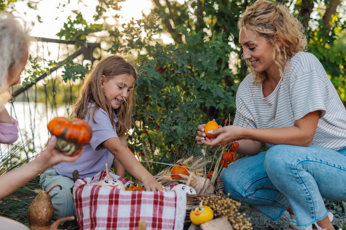 Mother and daughter decorating pumpkins and gourds for autumn festivities